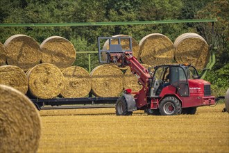 Straw bales, round bales, are loaded onto a trailer after the grain harvest, near Neuss North