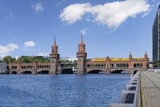 Yellow S-Bahn crossing the Double deck Oberbaum bridge over the Spree river, Berlin, Germany,