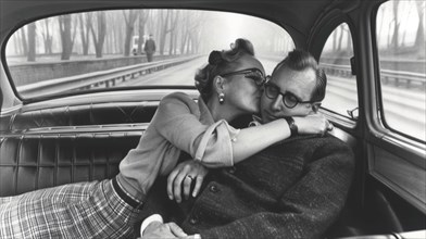 A black and white vintage photograph of a couple kissing inside a classic car, creating a nostalgic