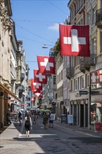 The Multergasse, pedestrian zone, shopping alleyway, decorated with Swiss national flags in the