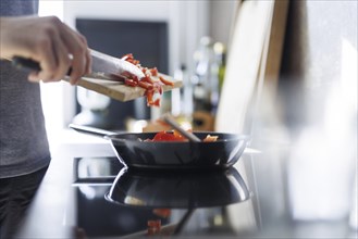 Cooking topic. A man shoves pieces of pepper into a pan to fry them. Berlin, 01.08.2024