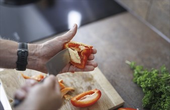 Cooking topic. A man cuts a sweet pepper. Berlin, 01.08.2024