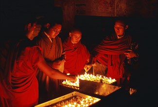 Tibetan buddhist monks and nun are lighting candles at night during the Buddha purnima festival