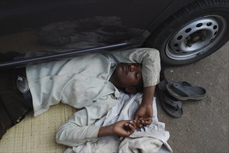 Man sleeping under a car (Mumbaï, India) . He belongs to the dalit community