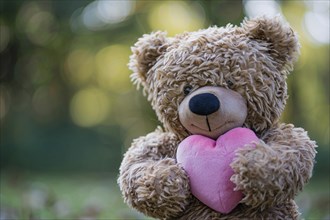 Cute teddy bear plush toy holding pink heart. Generative AI, AI generated