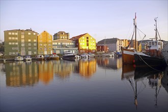 Colourful buildings and boats are reflected in the calm waters of a harbour, Nidarelva, Trondheim,