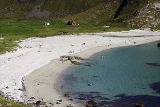 A white sandy beach with people, turquoise water and cliffs in the background, Haukland, Leknes,