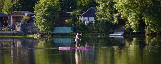 Panorama Hengsteysee with stand-up paddler in front of allotment gardens on the shore, Hagen, North