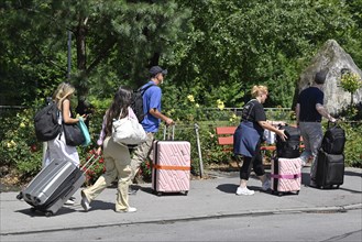 Tourists with wheeled suitcases