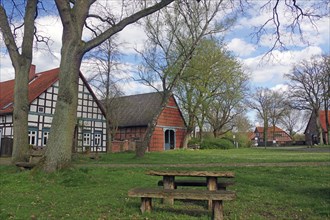 Picnic table under trees in front of half-timbered houses in a rural setting in spring, Satemin,