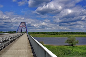 Bridge over a river under a cloudy blue sky, surrounded by green landscape, Dömnitzer Brücken,