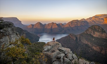 Young woman sitting on a rock, enjoying the view, sunset at Blyde River Canyon, view of canyon with