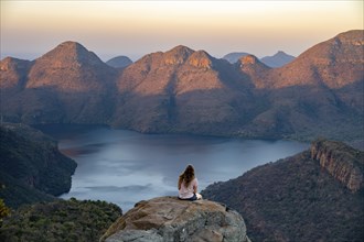 Young woman sitting on a rock, enjoying the view, sunset at Blyde River Canyon, view of canyon with