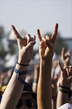 Metal fans show the French fries fork, a greeting in the metal scene, at the Wacken Open Air in