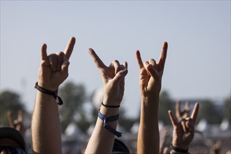 Metal fans show the French fries fork, a greeting in the metal scene, at the Wacken Open Air in