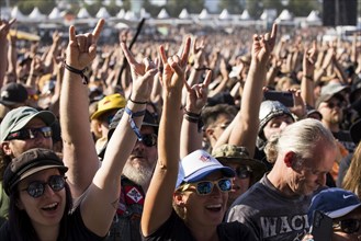 Metal fans show the French fries fork, a greeting in the metal scene, at the Wacken Open Air in