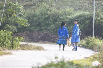 Two woman from the Hmong minority walk in everyday clothes on a street, Du Gia, Ha Giang province,