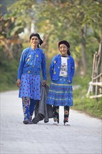 Two Hmong minority woman in everyday clothes stand on a street and look into the camera, Du Gia, Ha