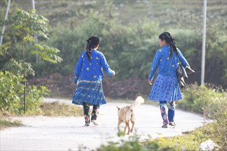 Two Hmong minority woman walk in everyday clothes on a street, Du Gia, Ha Giang province, Vietnam,