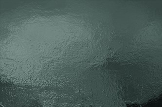 Abstract green textured image with a reflective, glossy and wavy surface resembling water