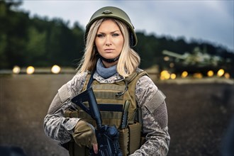 Woman in military uniform and helmet holding a gun in front of a tank on a forest road, AI