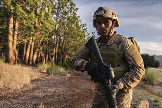 An armed soldier in nature with a helmet, in camouflage uniform concentrated in a wooded area, AI