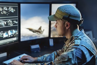 A soldier concentrates on watching aircraft simulations on large monitors in the control room, AI