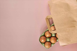 Kraft bag with chicken eggs in tray on beige background, shopping concept, space for text