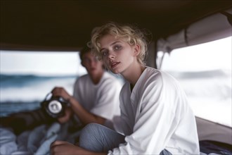 Woman sitting inside a tent with a man in the background, offering an intimate and artistic scene