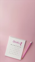 October calendar with a breast cancer awareness pink ribbon and a pencil with copyspace. Vertical