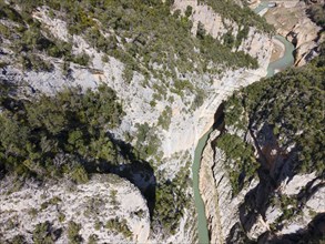 An aerial view of a deep, vegetation-rich gorge with a meandering river and steep rock faces,