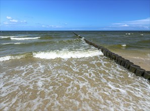 Sandy beach beach with wooden groyne in the Baltic Sea on the island of Usedom, clouds in the blue