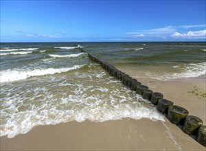 Sandy beach beach with wooden groyne in the Baltic Sea on the island of Usedom, clouds in the blue