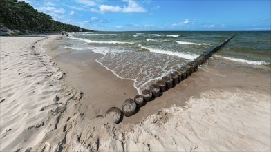 Sandy beach beach with wooden groyne in the Baltic Sea on the island of Usedom, clouds in the blue