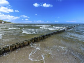 Sandy beach beach with wooden groyne in the Baltic Sea on the island of Usedom, clouds in the blue