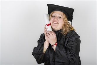 Recent graduate woman, dressed in cap and gown, showing off his degree