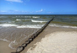 Sandy beach beach with wooden groyne in the Baltic Sea on the island of Usedom, clouds in the blue