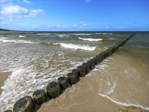 Sandy beach beach with wooden groyne in the Baltic Sea on the island of Usedom, clouds in the blue