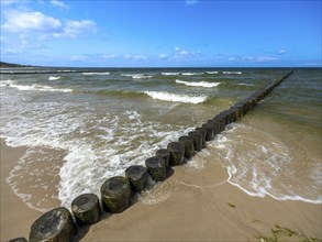 Sandy beach beach with wooden groyne in the Baltic Sea on the island of Usedom, clouds in the blue