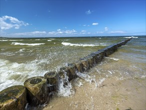 Spray splashes on a wooden groyne on a sandy beach on the Baltic Sea on the island of Usedom,