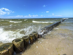 Spray splashes on a wooden groyne on a sandy beach on the Baltic Sea on the island of Usedom,