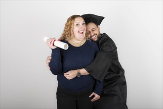 Recent graduate man, dressed in cap and gown, showing off his degree celebrating with his family