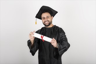 Recent graduate man, dressed in cap and gown, showing off his degree