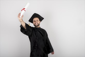 Recent graduate man, dressed in cap and gown, showing off his degree