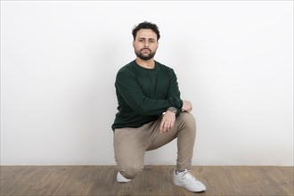 Man kneeling on the floor looking with serious expression at the camera