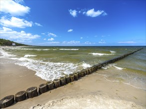 Sandy beach beach with wooden groyne in the Baltic Sea on the island of Usedom, clouds in the blue