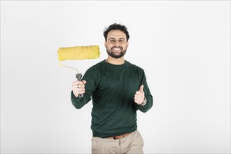 Smiling man holding a paint roller and giving thumbs up