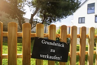 Sign with the inscription GRUNDSTÜCK ZU VERKAUFEN on a wooden fence (symbolic image)