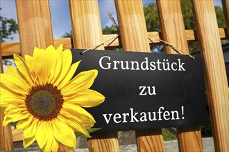 Sign with the inscription GRUNDSTÜCK ZU VERKAUFEN on a wooden fence (symbolic image)