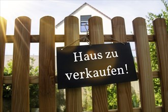 Sign with the inscription HAUS ZU VERKAUFEN on a wooden fence (symbolic image)